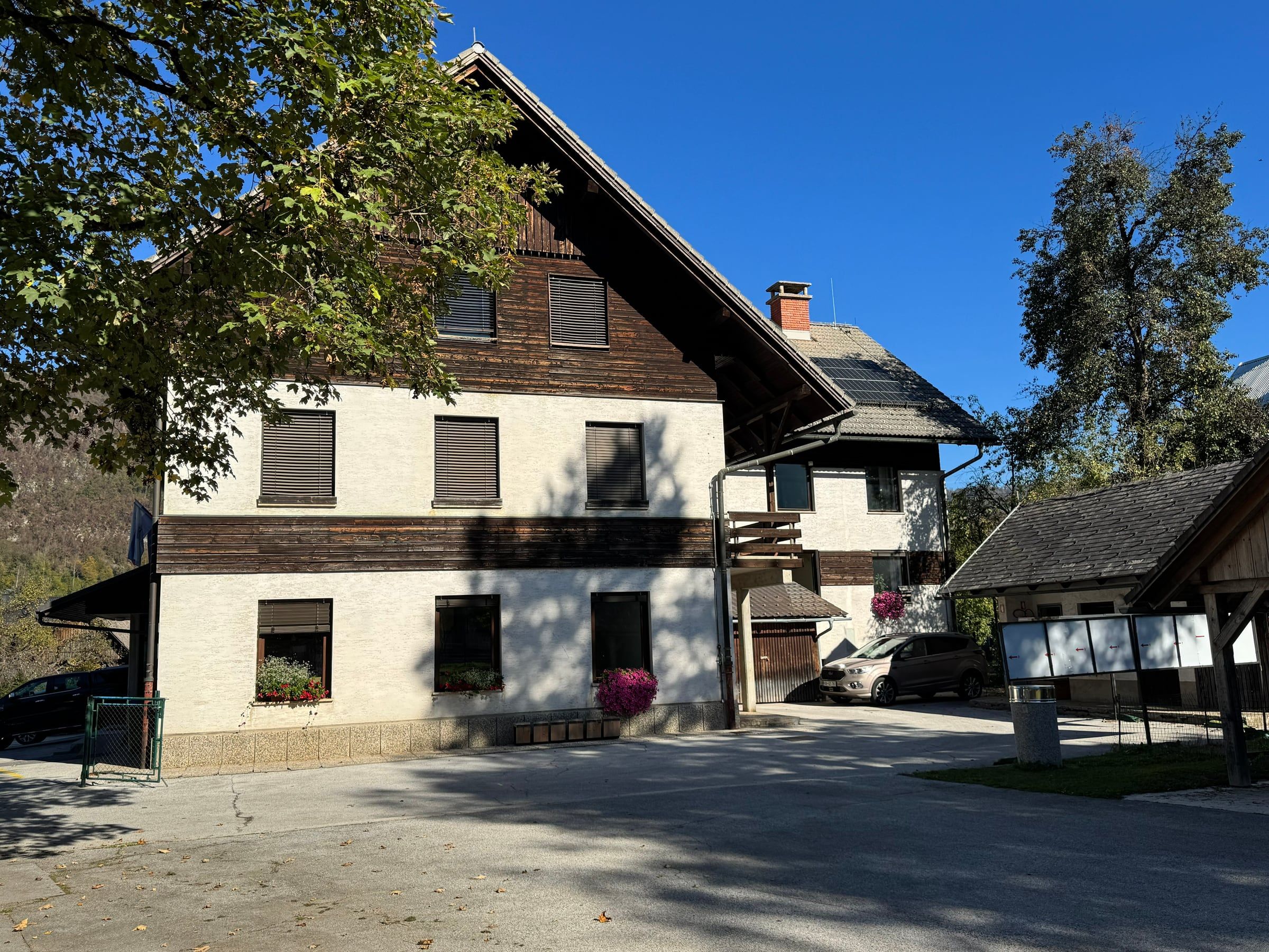 Bohinjska hiša, obnovljena alpska hiša z lesenim nadstropjem in oglasno desko pred njo