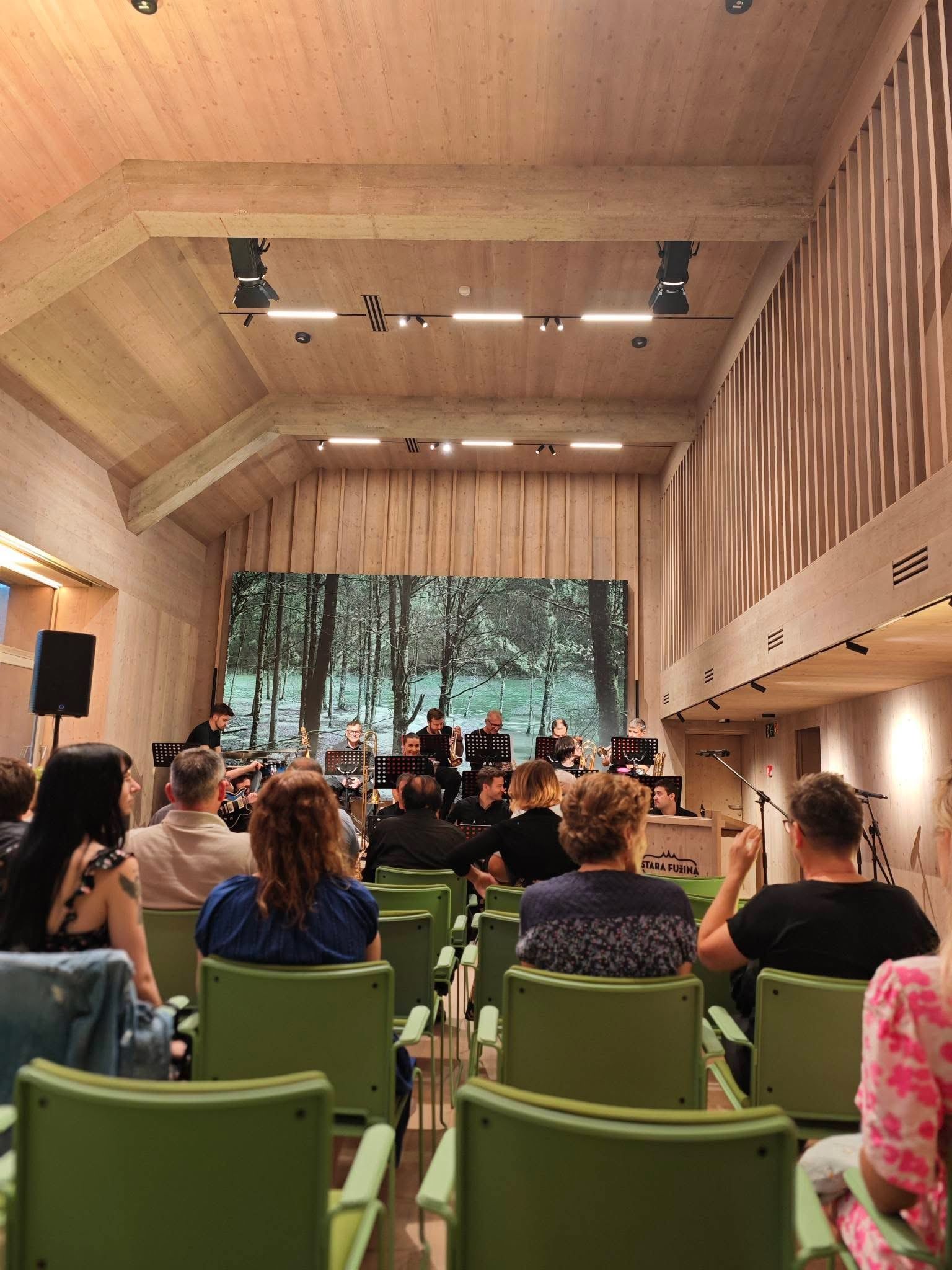 Koncert v obnovljenem kulturnem domu v Stari Fužini, občinstvo in glasbeniki na odru