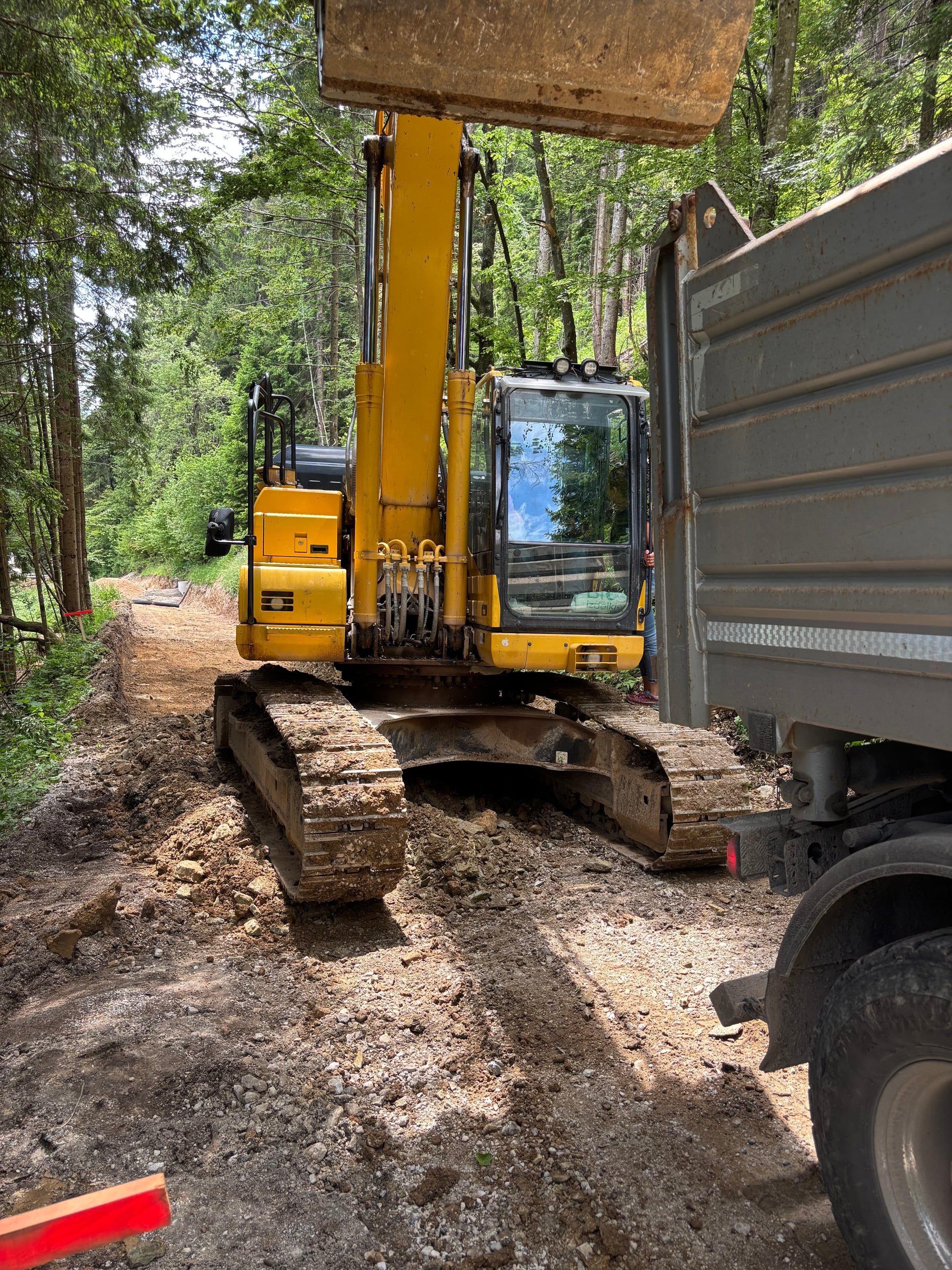 Bager koplje jarek za komunalno infrastrukturo ob gozdni cesti